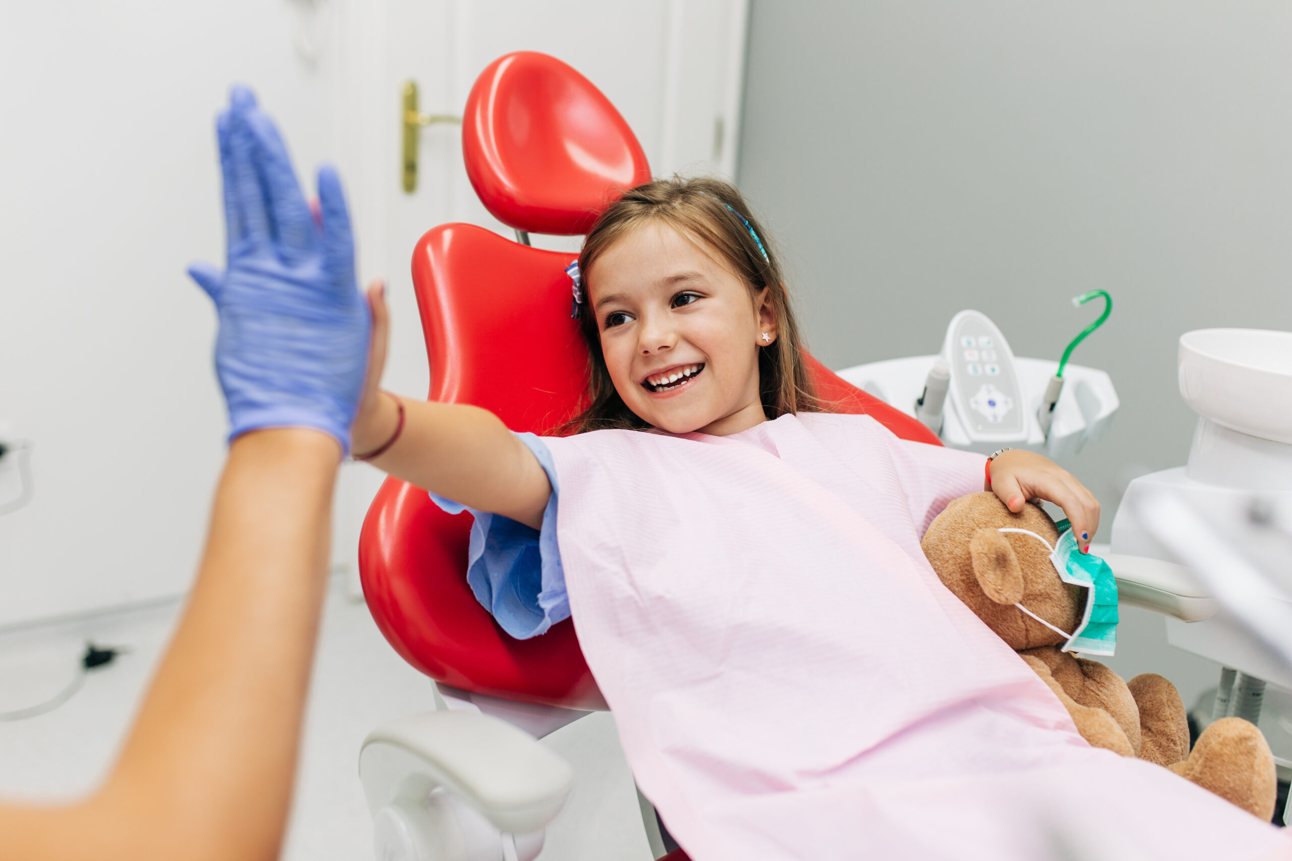 Cute little girl sitting on dental chair and having dental treatment